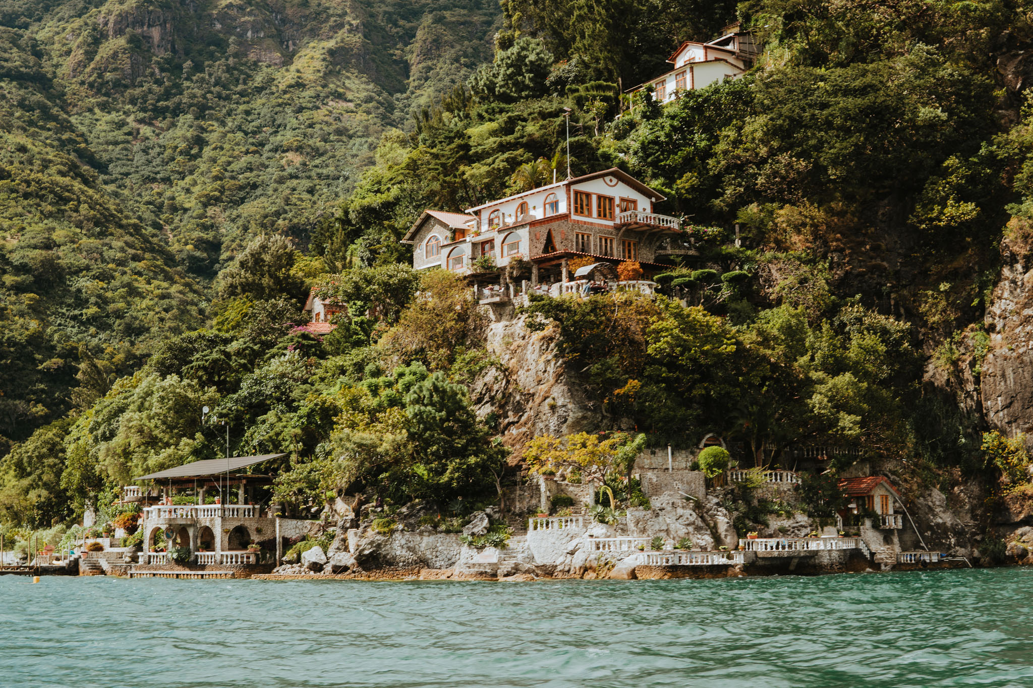 Scenic view looking up at Hotel Casa Del Mundo perched cliffside, view from the water